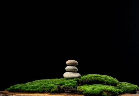 Stack of round stones on green moss, black background. Podium to showcase ... Foto stock