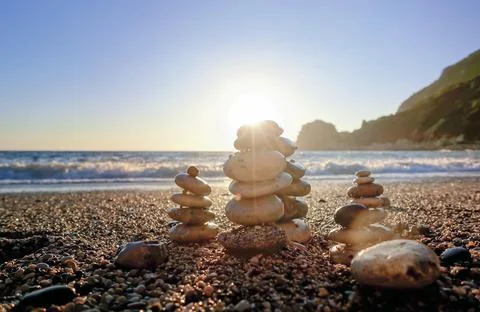Stack of round stones standing on the shore of a sea. Stock Photos