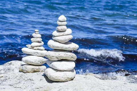 Stack of round white stones standing on the shore of a sea. Stock Photos