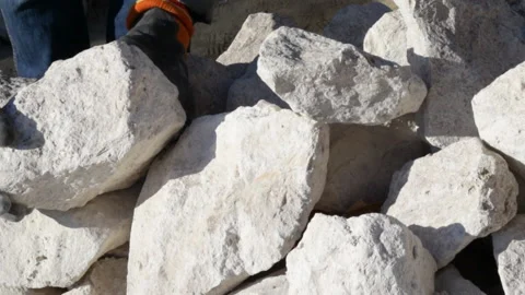 Stack of rubble stones outside, sunny day, and a man is taking some pieces. Vídeos de archivo 181971105