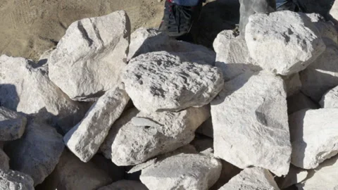 Stack of rubble stones outside, sunny day, and a man is taking some pieces. Video stock 181973329