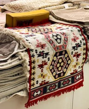 Stack of rugs with traditional patterns and colors folded in a market stall.  Stock Photos