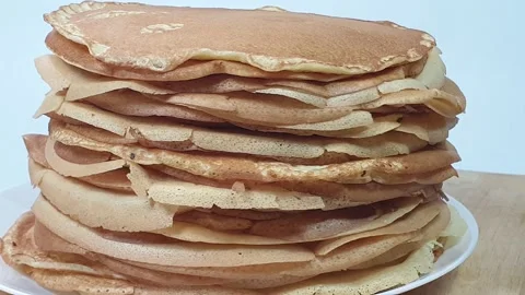 A stack of Russian pancakes on a white background on a wooden board, pancakes on Vídeos de archivo 150449337
