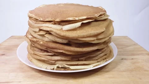 A stack of Russian pancakes on a white background on a wooden board, pancakes on Vídeos de archivo 150450625