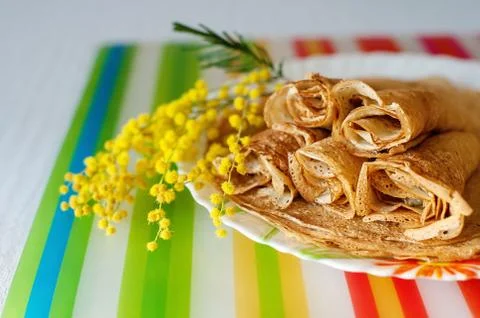 Stack of Russian-style pancakes and a branch of a blossoming mimosa. Spring Stock Photos