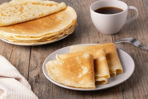 Stack of Russian thin pancakes and coffee on a wooden table Stock Photos
