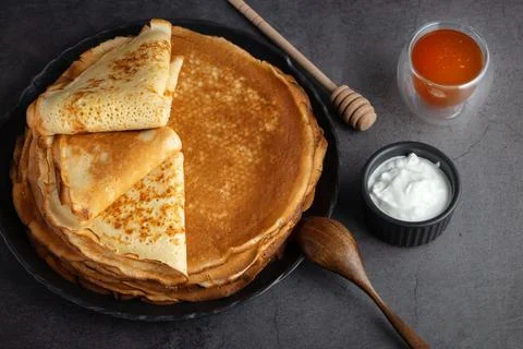 Stack of russian thin pancakes blini with fresh sour cream and honey Stock Photos