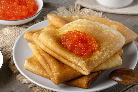 Stack of russian thin pancakes blini with red caviar on an old wooden table Foto stock