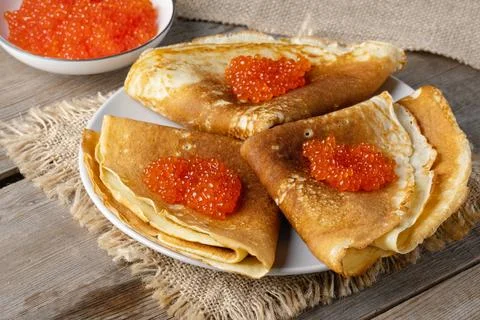 Stack of russian thin pancakes blini with red caviar on an old wooden table 스톡 사진