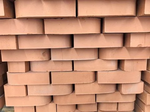 Stack of rustic clay bricks awaiting construction at a sunny site 库存照片