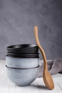 Stack of rustic style handcraft bowls in neutral tones with wooden spoon. Stock Photos