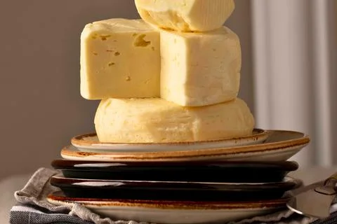 Stack of rustic yellow cheese blocks on plates Stock Photos