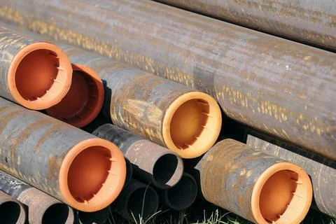 Stack of rusty steel pipes with orange caps on grass Stock Photos