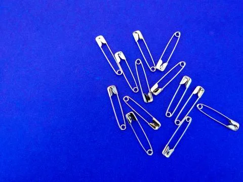 Stack of Safety pins on blue background. Copy space. Selective focus Stock Photos