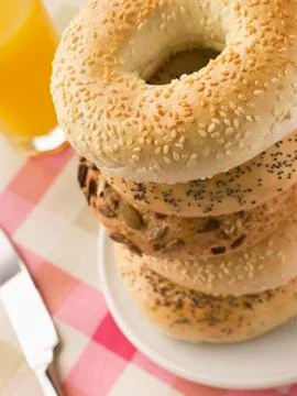 Stack of Seeded Bagels with a Glass of Orange Juice Stock Photos