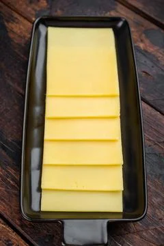 Stack of semi hard yellow cheese slices arranged on black tray, dairy ingre.. Stock Photos