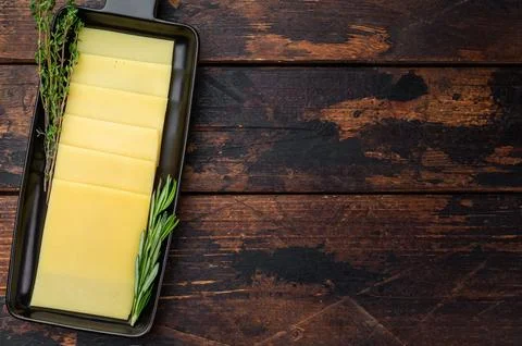 Stack of semi hard yellow cheese slices arranged on black tray, dairy ingre.. Foto stock