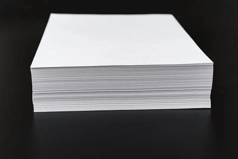 A stack of sheets of white paper on a black background. Stock Photos