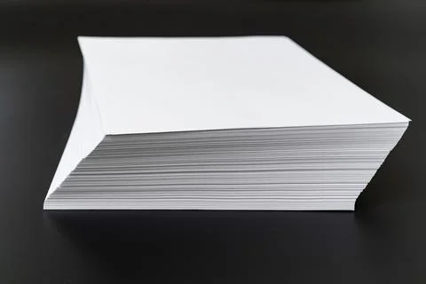 A stack of sheets of white paper on a black background. Stock Photos