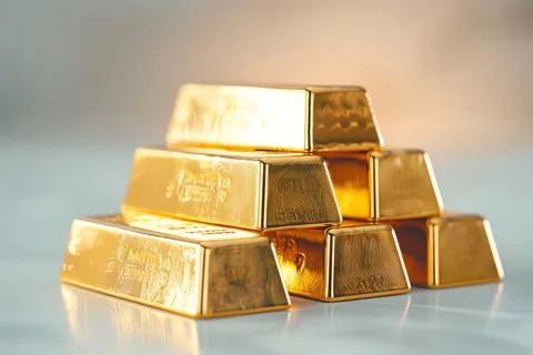 A stack of shining gold bars on a reflective surface with a soft background.  Foto stock