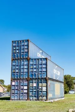 Stack of shipping containers on green grass under clear blue sky Stock-Fotos