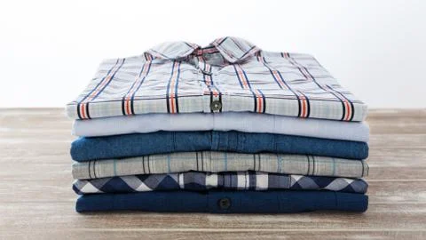 Stack of shirts on wooden table Stock Photos
