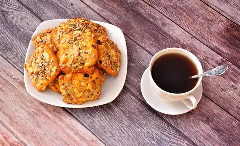 A stack of shortbread cookies with sesame and peanuts on a plate and a cup of Stock Photos