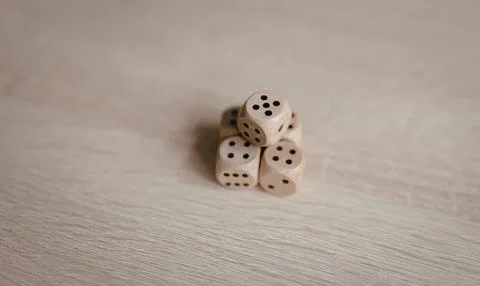 Stack of six white dice with black dots on light wooden surface 写真素材