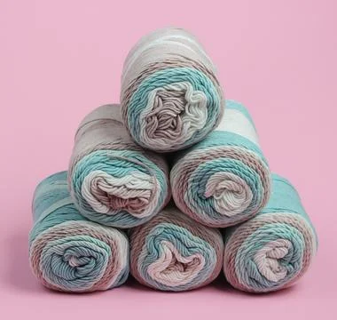 Stack of skeins of woolen threads close-up on pink pastel background Stockfoto's