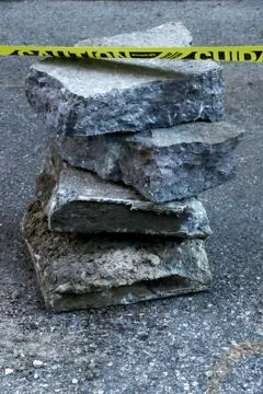 A stack of slabs of pavement with caution sign Stock Photos