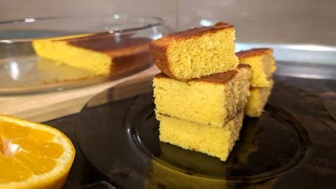Stack Of Sliced Homemade Orange Sponge Cake On Dark Glass Plate Foto stock