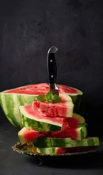 Stack of slices of ripe red watermelon in a metal plate, stuck in a large ... Stock Photos