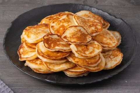 Stack of small pancakes on a black plate ready for breakfast at the kitchen.. Stock Photos