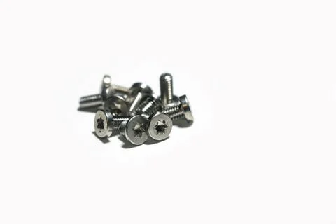 A stack of small screws on a white background macro photo. Stock Photos