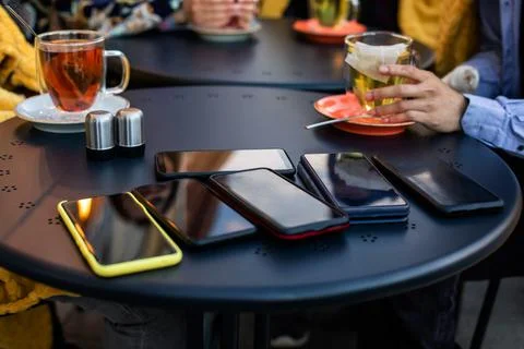 Stack of smartphones on black table at the cafe Stock Photos