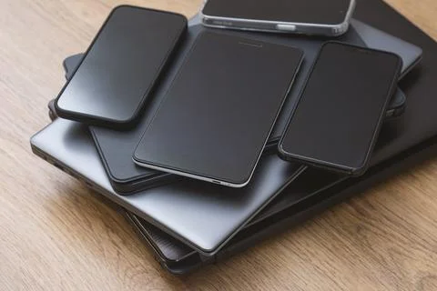 Stack smartphones, tablets, and laptops on a wooden table, showcasing moder.. Foto stock