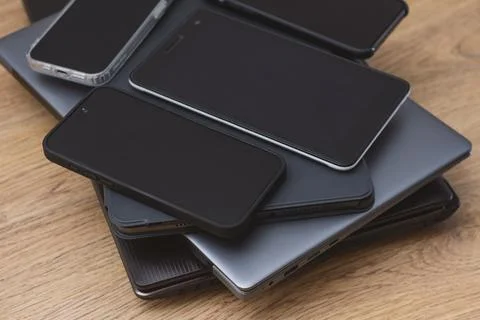 Stack smartphones, tablets, and laptops on a wooden table, showcasing moder.. Foto stock