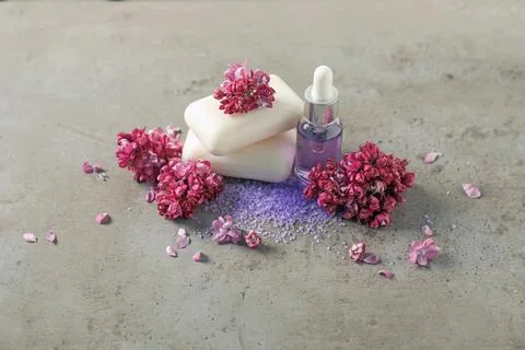 Stack of soap bars, essential oil, sea salt and lilac flowers on grey textu.. Stock Photos
