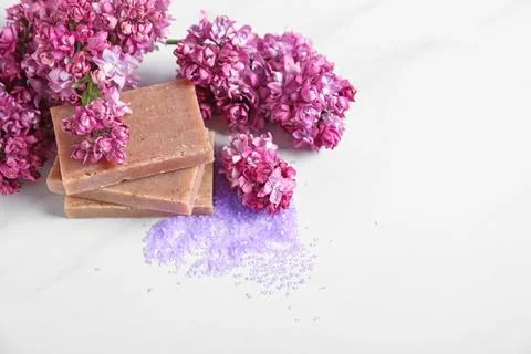 Stack of soap bars, sea salt and lilac flowers on white table. Space for text Stock Photos