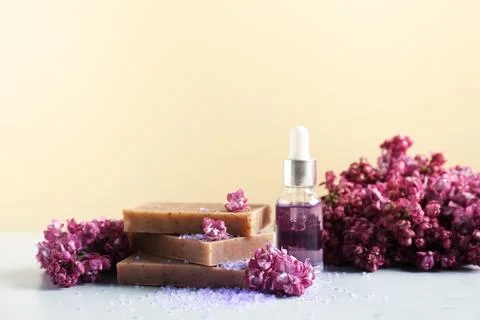 Stack of soap bars, sea salt, essential oil and lilac flowers on white tabl.. Stock Photos