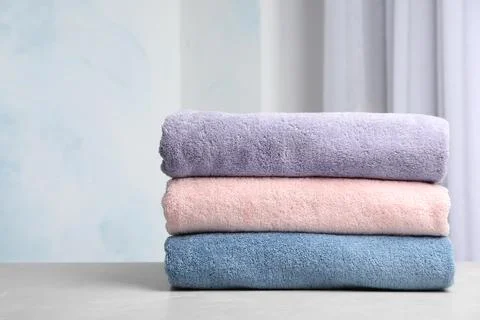 Stack of soft bath towels on table against blurred background. Space for text Stock Photos