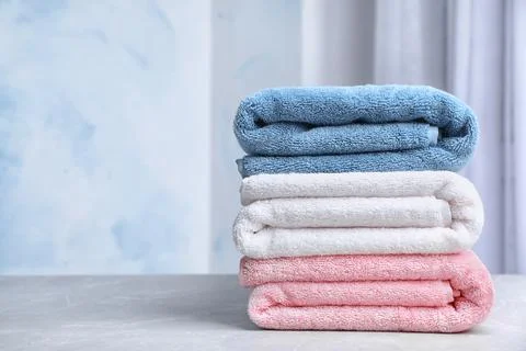 Stack of soft bath towels on table against blurred background. Space for text Foto stock
