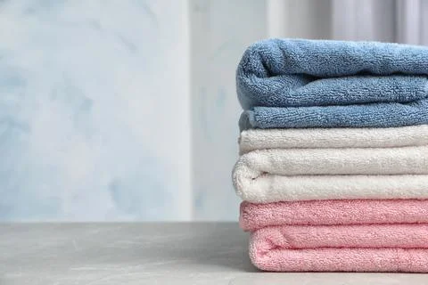 Stack of soft bath towels on table against blurred background. Space for text Foto stock