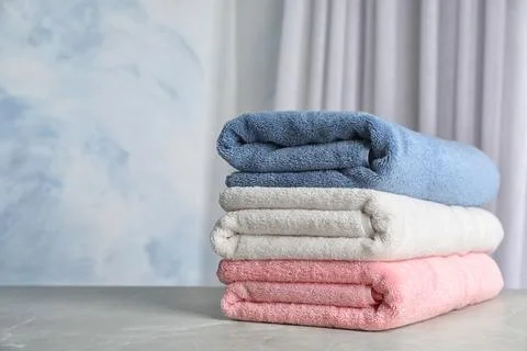 Stack of soft bath towels on table against blurred background. Space for text 스톡 사진