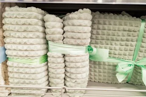 Stack of soft beige blankets tied with green ribbons in store display Stock Photos