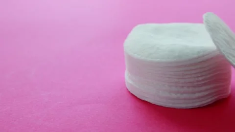 A stack of soft cotton pads for face and skin care on a pink background, close Stock Footage 253470697