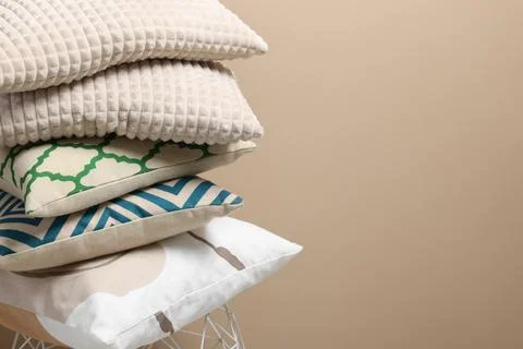 Stack of soft pillows on small table near beige wall. Space for text Foto stock