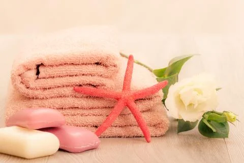 Stack of soft terry towels with soap and flower on wooden boards. Stock Photos