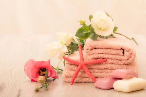 Stack of soft terry towels with soap and flower on wooden boards. Stock Photos