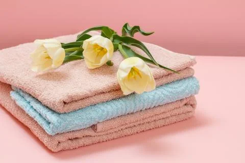 Stack of soft terry towels with tulips on a pink background. Stock Photos